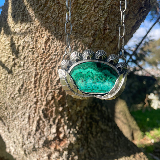 Necklace with a green stone pendant on a tree trunk
